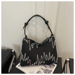 Detail of black tote bag featuring colorful embroidery waves and knotted leather handle