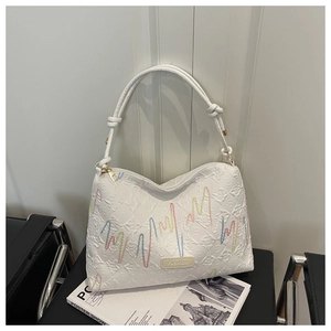 Close-up of textured white tote with wave embroidery and knotted strap detail