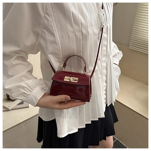 Gros plan d'un mini sac à main en cuir verni bordeaux avec fermoir rotatif doré