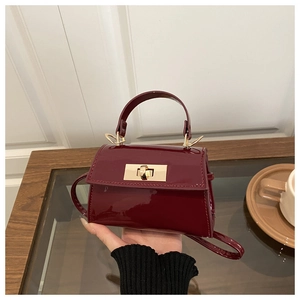 Détail macro du mini sac en cuir verni bordeaux avec fermoir rotatif doré élégant