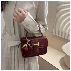 Close-up of wine red crocodile pattern handbag with gold H buckle and cherry charm