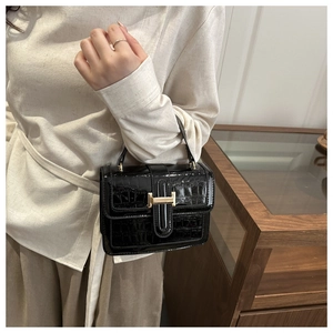 Fashionable black crocodile pattern handbag with golden H-buckle shown on model