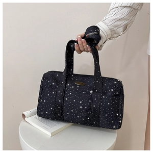 Detail of black Boston bag with white star patterns and oval logo plaque on canvas