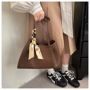 Brown tote bag with decorative patterned silk scarf handle in a minimalist autumn outfit