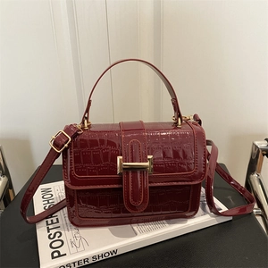 Glossy burgundy crocodile pattern handbag with gold clasp and adjustable shoulder strap