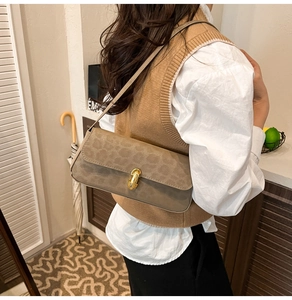 Detail of leopard print shoulder bag with gold spindle clasp and khaki strap on model