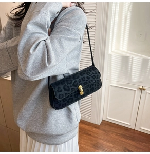 Close-up of leopard print baguette bag with gold metal buckle on casual outfit