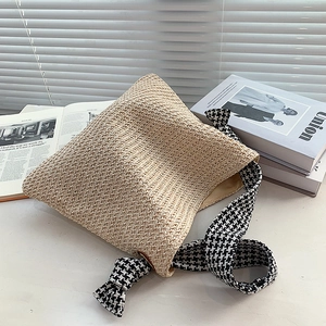 Minimalist straw shoulder bag with houndstooth strap shown in aesthetic setting