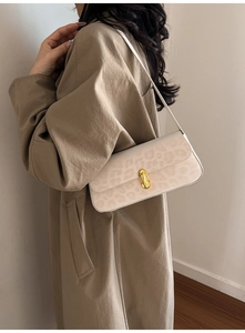 Detail of cream leopard print underarm bag with gold metal buckle on beige trench coat