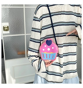 Detail of creative cupcake shaped crossbody bag with heart pattern and blue shoulder strap