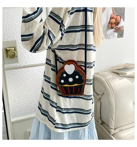 Detail of cupcake shaped crossbody bag with polka dots and heart on a model
