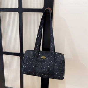 Boston barrel bag with star pattern and metal logo plaque on vintage door frame