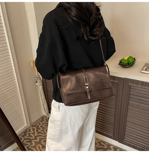 Macro view of vintage dark brown leather shoulder bag with golden metallic fastener