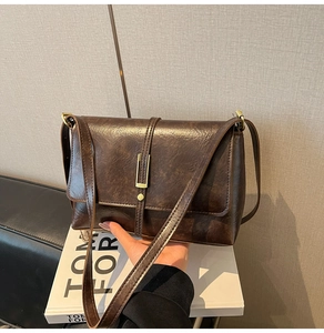 Close-up of brown vintage PU leather tote bag with gold metal buckle and textured surface
