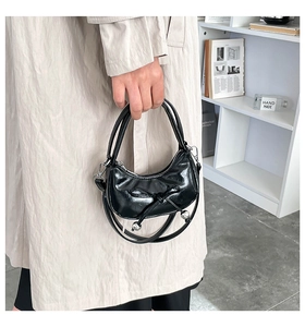 Détail du sac croissant noir brillant avec nœud en ruban et perles métalliques argentées