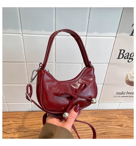 Détail du mini sac bordeaux en cuir brillant avec nœud décoratif et perles argentées