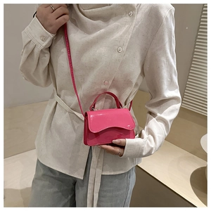 Detail of bright pink patent leather mini bag with unique wavy flap and matching strap