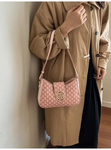 Detail of pink shoulder bag with M-letter print and golden round logo buckle