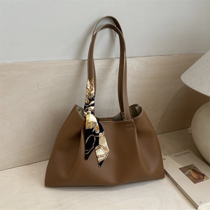 Minimalist brown tote bag with silk scarf on textured surface and white background