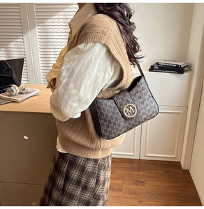 Detailed side view of a brown monogram shoulder bag with a gold metal M logo buckle