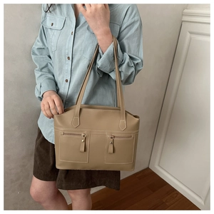 Detail of khaki tote bag featuring dual front zipper pockets and matte texture finish