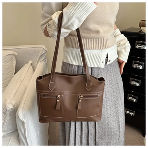 Detail of vintage brown leather shoulder bag with parallel zippers and white stitching