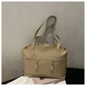 Detail of beige faux leather tote bag with two front zipper pockets and shoulder strap