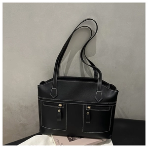 Detail of black tote bag with white contrast stitching and gold metal rivet accents