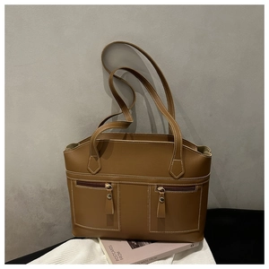 Close-up of caramel brown tote bag featuring white contrast stitching and dual zip pockets