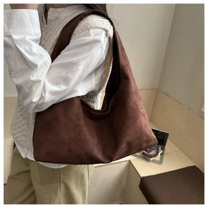 Detail of dark brown suede hobo bag shown in a minimalist lifestyle setting for women