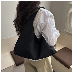 Minimalist black faux suede shoulder bag shown from behind on a person in cozy room