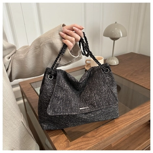 Close-up of a large grey tweed tote bag with metal chain strap and minimalist buckle