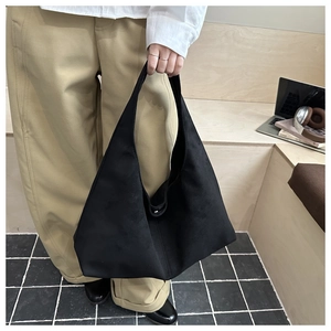 Large black matte tote bag with smooth lines shown in a minimalist urban lifestyle setting