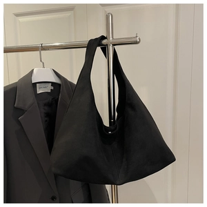 Detailed close-up of matte black suede hobo bag with a minimalist triangular structure