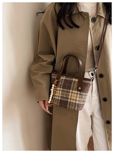 Detail of plaid wool tote bag with brown leather handles and beaded tassel charm accent