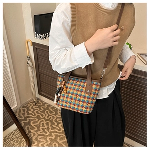 Detail of checkered houndstooth tote bag with leather handles and wooden bead charm