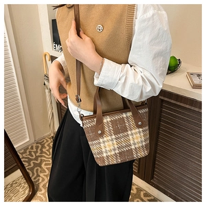 Close-up of brown plaid tweed tote bag with leather handle and adjustable strap detail