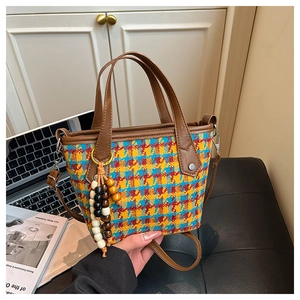 Detail of multi-color tweed tote bag with leather handles and decorative bead tassel