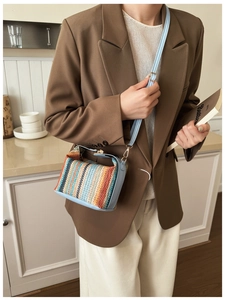 Detail of colorful striped woven texture and light blue leather trim on women's handbag