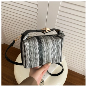 Détail du sac à main tissé à rayures avec fermoir doré et poignée en cuir noir élégant