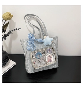 Detail of silver pleated ita bag with transparent window, lace ribbon and star plush charm