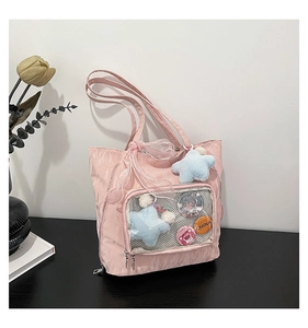 Detail view of pink nylon ita bag with a transparent window featuring star plush and badges
