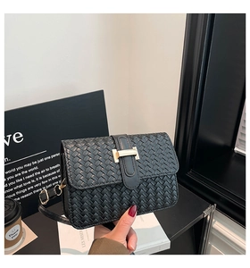 Detail of black woven leather square bag featuring a gold H-shaped metal buckle and strap
