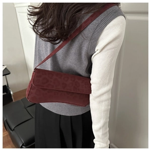 Detail of burgundy underarm bag featuring leopard print texture and matte finish leather