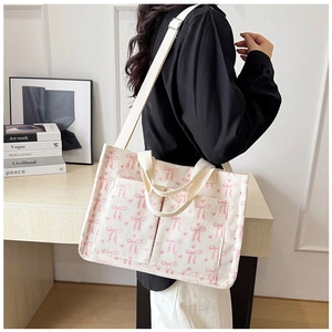 Close-up of cream corduroy tote bag with pink bow prints and adjustable shoulder strap