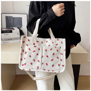 Close-up of strawberry print corduroy tote bag showing large front pockets and dual straps
