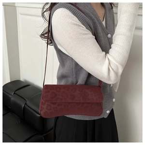 Detail of dark burgundy underarm bag featuring leopard embossed texture and sleek strap