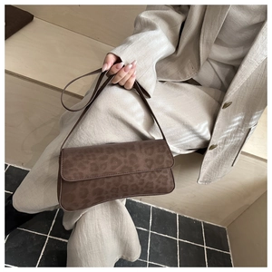 Close-up of a leopard print faux suede underarm bag styled with a beige linen suit