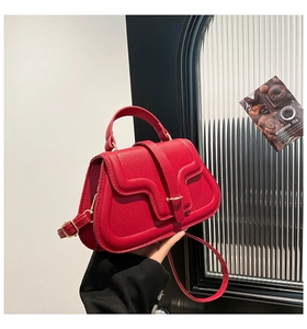Detail of red pebbled leather handbag with wavy stitching and gold metal lock clasp