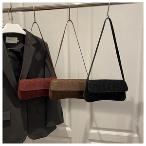 Detailed view of leopard print shoulder bags in red, brown, and black suede texture